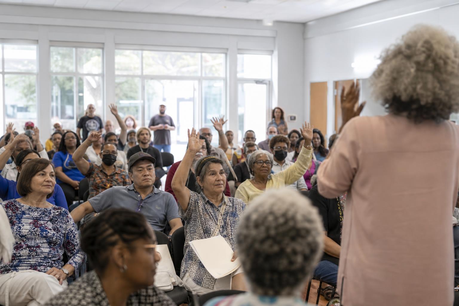 Engaged audience raising hands at a community town hall meeting